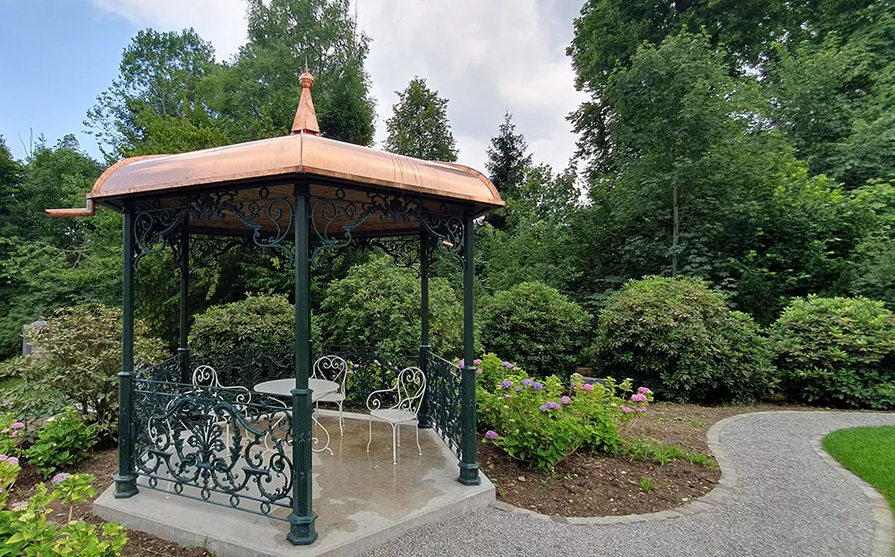 handgeschmiedeter gartenpavillon aus kunstvoll bearbeitetem metall mit filigranen ornamenten und massiven stützen, metallgestaltung kunstschmiede appenzell