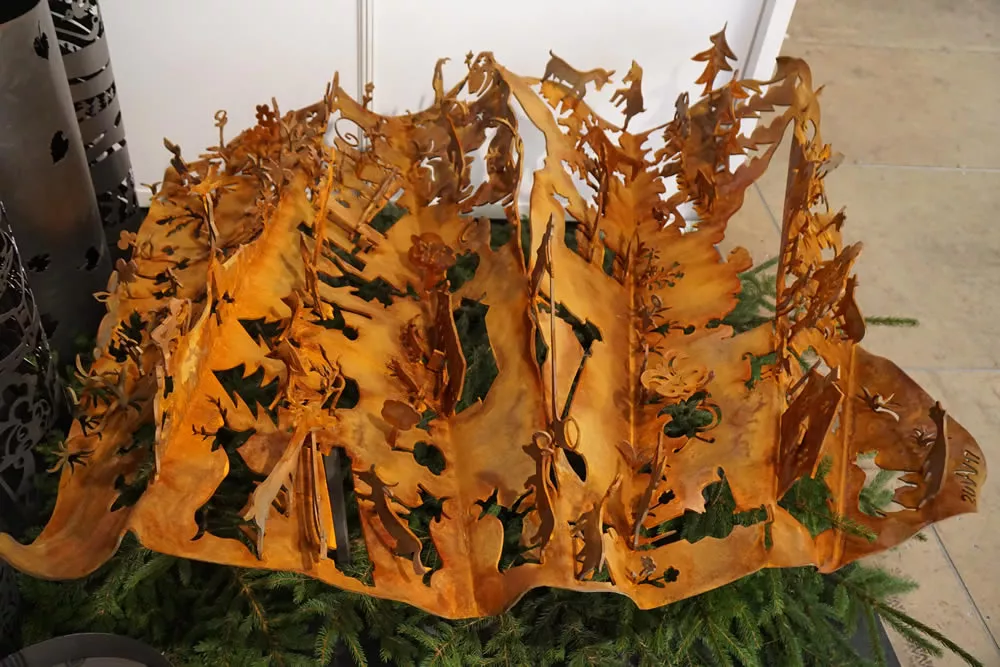 aufwendig ausgeschnittene metallskulptur mit szenen und bäumen aus rostpatiniertem stahl, handgeschmiedete kunstarbeit kunstschmiede appenzell